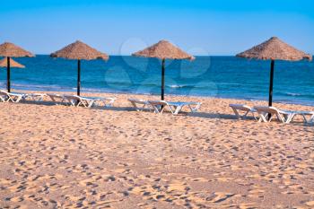 straw beach umbrellas on ocean coast, Portugal, Algarve