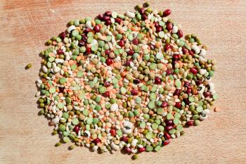 mix of different dry beans for Italian lentil soup on wooden board in summer day