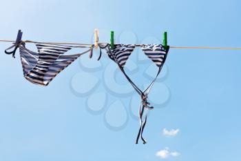 drying woman swimming suit with blue sky background