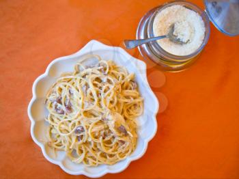 Plate with spaghetti alla carbonara and grated cheese