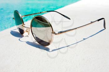 black round sun glasses on pool in summer day