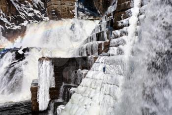 rainbow on river waterfall cascade in mountain gorge in winter