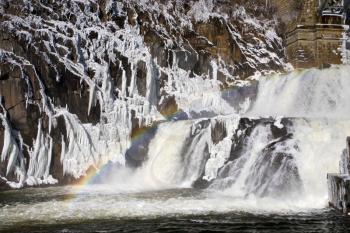 rainbow on river dam cascade in winter