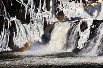 rainbow on river dam cascade in winter