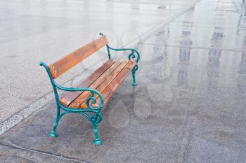 solitary wood bench in the rain on urban square