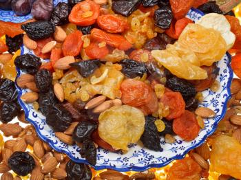 many dried fruits on asian plates close up