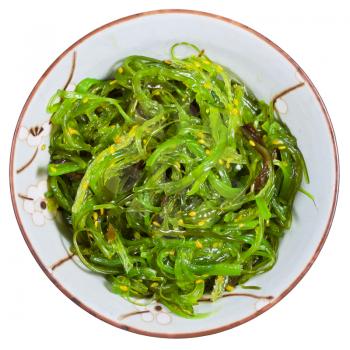 top view of chuka salad - seaweed salad sprinkled with sesame seeds in bowl isolated on white background