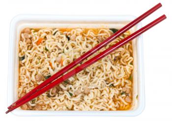 top view of cooked instant noodles and red chopsticks in foam cap isolated on white background