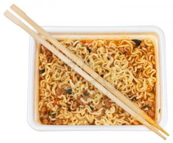 top view of cooked instant ramen and wooden chopsticks in foam cap isolated on white background