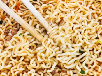 eating of cooked instant noodles by wooden chopsticks close up