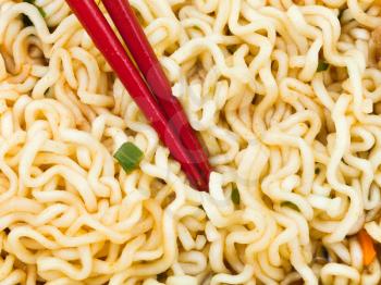 eating of cooked instant ramen by red chopsticks close up