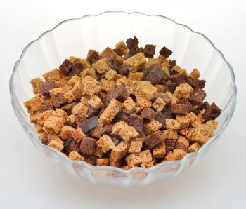dried rye bread crust pieces in glass bowl on white table
