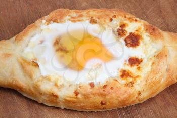 hachapuri by Adzharia (Georgian cheese pastry), filled with cheese and topped with a soft-boiled egg and butter on wooden board