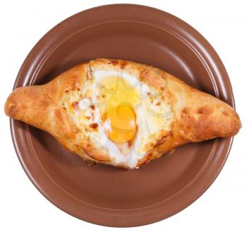 top view of Ajarian khachapuri (Georgian cheese pastry), filled with cheese and topped with a soft-boiled egg and butter on ceramic plate isolated on white background