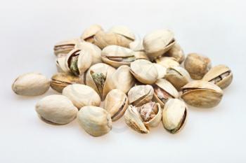 many salted pistachio nuts close up on white background
