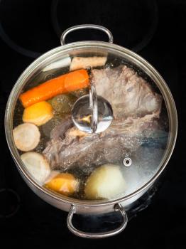 boiling of beef broth with seasoning vegetables in stew pan on glass ceramic cooker