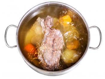open pan with cooking beef broth with with seasoning vegetables isolated on white background