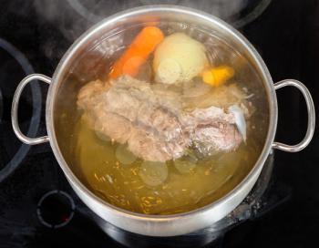 simmer of beef broth with seasoning vegetables in pan on glass ceramic cooker