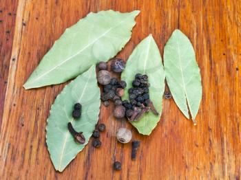 aromatic bay leaves and black pepper seeds on wooden table