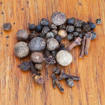 macro view of spicies from black peppers, allspices, cloves on wooden table