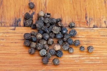 black peppercorns on wooden table close up