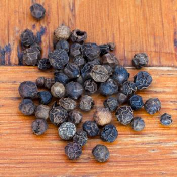 black pepper seeds on wooden table close up