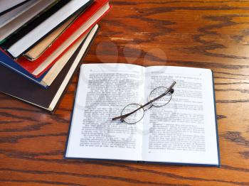 above view of blank open book and glasses on wooden table
