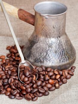 roasted coffee beans and copper coffee pot close up on sacking