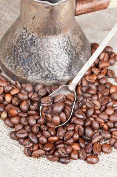 roasted coffee beans and copper coffee pot close up on sackcloth
