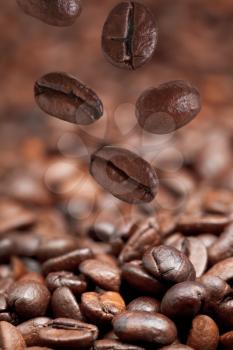 few falling beans and dark roasted coffee beans background with focus foreground