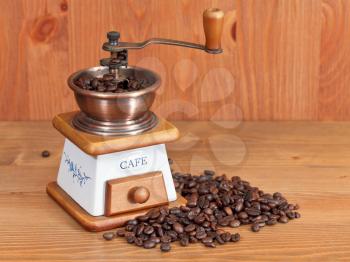 heap of coffee and vintage manual coffee mill on wooden table