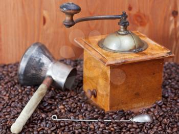 retro manual coffee grinder , copper pot, spoon on many roasted coffee beans