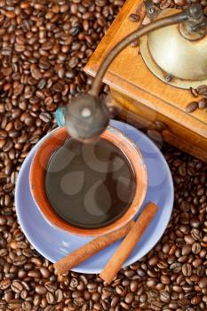 top view mug of coffee and roasted coffee beans with retro wooden manual mill, cinnamon
