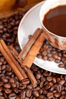 cup of coffee and roasted coffee beans with cinnamon close up