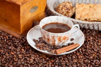 cup of coffee and roasted coffee beans with retro wood manual mill, biscuit, cinnamon
