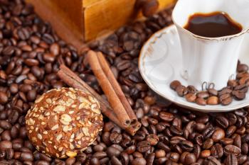 small cup of coffee and roasted coffee beans with retro wooden manual mill, cinnamon, biscuit close up