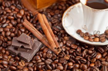 small cup of coffee and roasted coffee beans with retro wooden manual mill, cinnamon, chocolate bars close up
