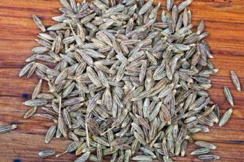 macro view of dried cumin seeds on wooden table