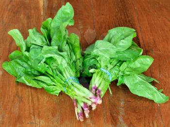 bunch of fresh green spinach on wooden table