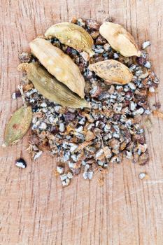 dried seeds and freshly milled cardamon spice on wooden board