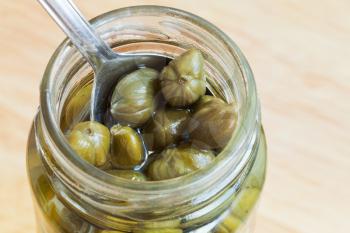 spoon in jar of pickled capers close up