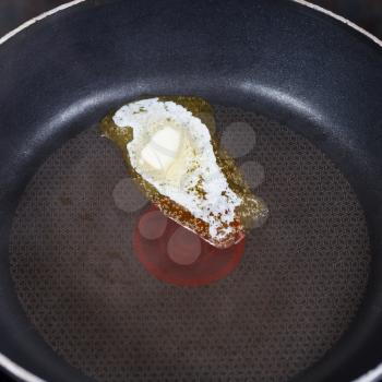 small piece dairy butter melting on hot frying pan close up