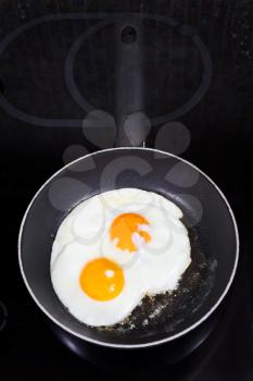 two prepared fried eggs in frying pan on electric stove