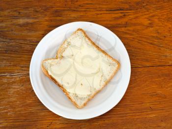 bread and butter sandwich on white plate on wooden table