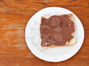 top view of sweet sandwich from fresh toast with chocolate spread, table knife on wooden table