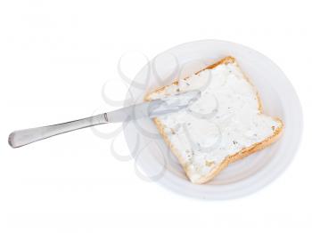 sandwich from toast and soft cheese with herbs on white plate, table knife isolated on white background