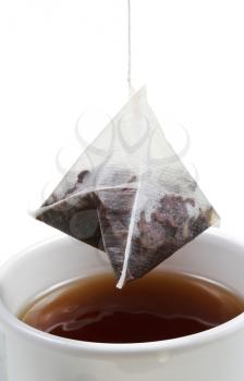 brewing of tea in mug with tea bag close up isolated on white background