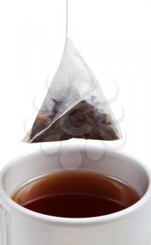 brewing of tea in cup with tea bag close up isolated on white background