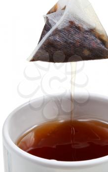 removing of tea bag from mug with brewing tea close up isolated on white background