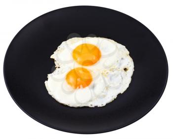 two fry eggs on ceramic black plate isolated on white background